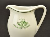 a white pitcher with a green design on it