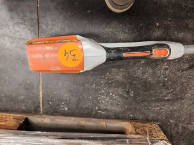 un aspirateur sans fil orange et blanc posé par terre