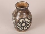 a small vase with a flower on it on a white surface