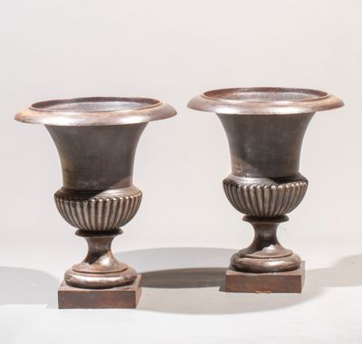 two silver vases sitting on top of a wooden stand
