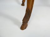une petite table en bois dont les pieds sont ornés d'un animal sculpté