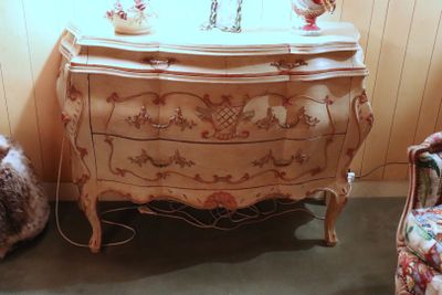 a dresser with a mirror on top of it next to a chair