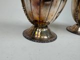 two silver vases sitting next to each other on a table