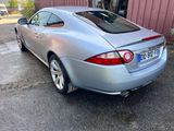the rear end of a silver sports car parked in front of a building