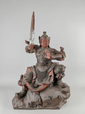 statue d'une femme tenant une épée, debout sur un rocher, sur fond blanc
