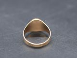a close up of a gold signet ring on a black surface