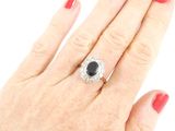 woman ' s hand with red manicured nails and a black and white diamond ring
