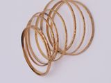six gold rings stacked on top of each other on a white surface