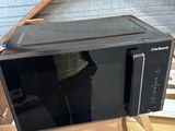 a black microwave sitting in a cardboard box on a table