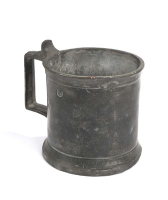 une petite tasse en métal avec une anse, posée sur une surface blanche