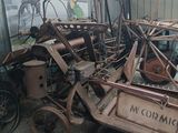 a pile of junk in a garage with a tractor in the background