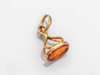 une photo d'un pendentif en or orné d'une pierre orange