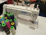une machine à coudre posée sur une table, avec de nombreuses bobines de fil