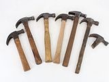 five old hammers are lined up on a white surface