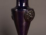 purple glass vase on a wooden table against a gray wall