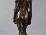 a bronze statue of a woman standing on a wooden base