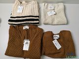 trois paires de pulls et un bonnet sont posés sur une table