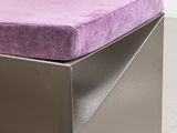purple cushion on a metal bench in a room with a white wall
