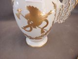 a white vase with gold decoration on it on a table