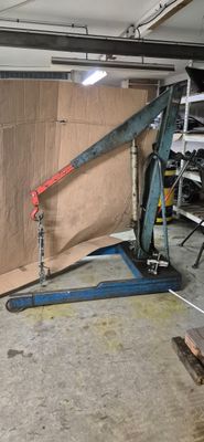 un homme debout dans un garage, tenant un gros morceau de bois