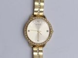 a gold wrist watch with a white face on a white surface