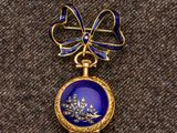 une image représentant une broche bleue et dorée ornée d'un nœud