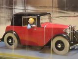 a red toy car with a man sitting in the driver ' s seat