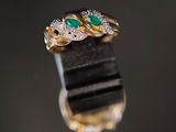 deux bagues en or ornées d'émeraudes et de diamants sur un fond noir