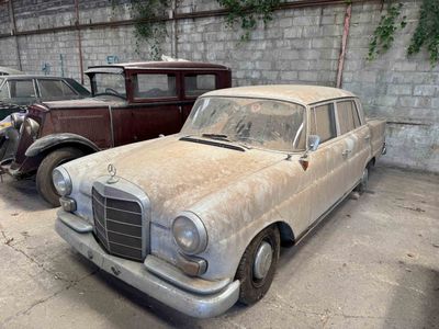 two old cars parked in a garage next to each other