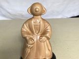 une petite figurine représentant un homme assis sur une table