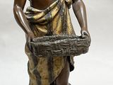 bronze statue of a man holding a basket and a dog
