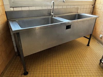 un évier en acier inoxydable dans le coin d'une salle de bains