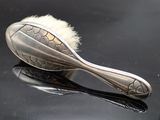 a silver spoon with a brush on top of it