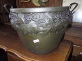 a large metal pot on a table with a bird on top of it