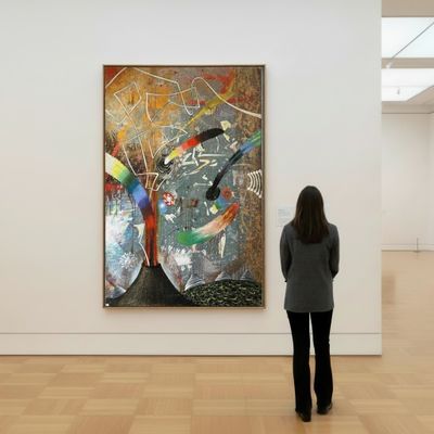a woman standing in front of a painting in a museum