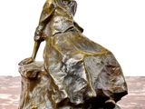 une statue en bronze d'une femme assise sur un rocher