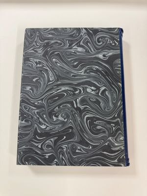 a black and white marbled notebook sitting on top of a white table