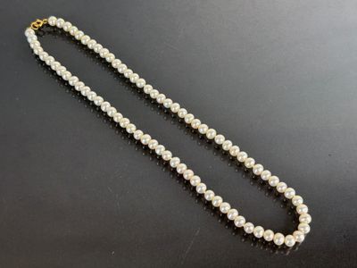 a close up of a white pearl necklace on a black surface