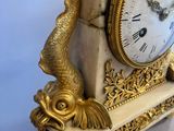 a clock that is sitting on a stand with a fish on it