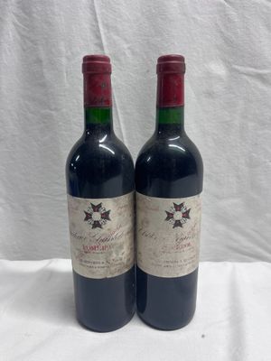 two bottles of red wine sitting on top of a white table