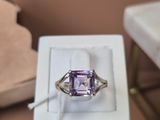 une bague en améthorate violette posée dans une boîte blanche sur une table