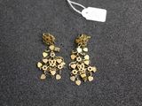 a pair of gold tone earrings on a black surface