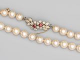 un gros plan sur un collier orné de perles et d'une pierre rouge