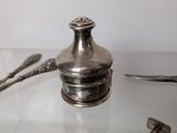 a silver object on a glass table with a spoon and spoon rest