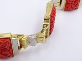 an image of a red bracelet with gold accents on a white surface