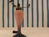a pink vase with a weather vane on top of it