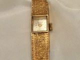 a gold watch that is laying on a white sheet