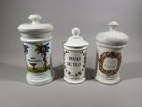 three white ceramic containers with designs on them sitting on a table