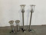 three different types of stainless steel outdoor lights on a concrete floor