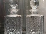 two clear glass bottles sitting on a glass table